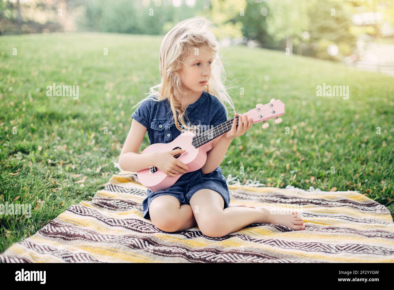 Süße liebenswert blonde Mädchen spielen rosa Gitarre Spielzeug im Freien. Kind spielt Musik und singt im Park. Hobby-Aktivität für Kinder Kinder. Ausschreibung Stockfoto