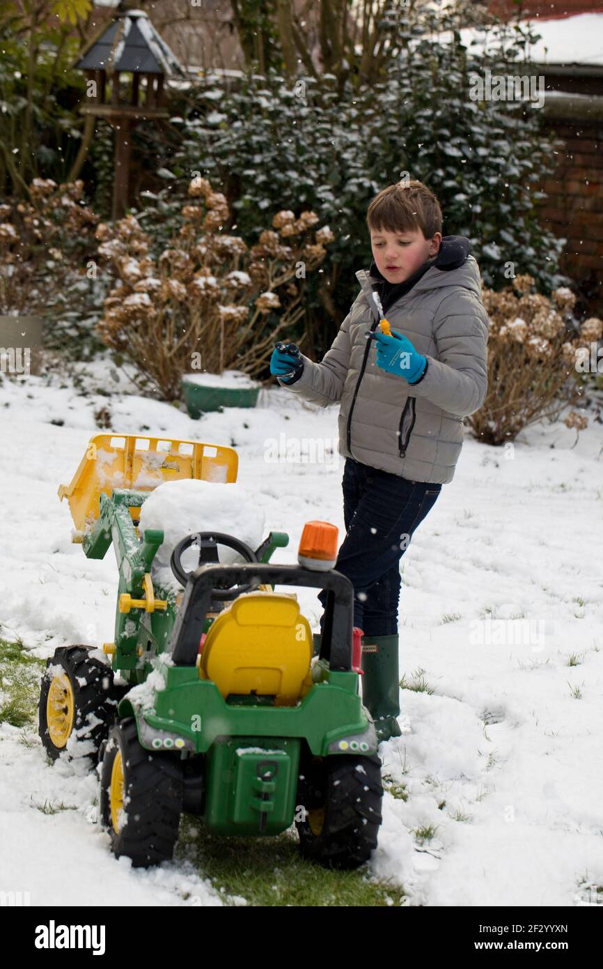 Ein achtjähriger Junge, der im Schnee spielt Stockfoto