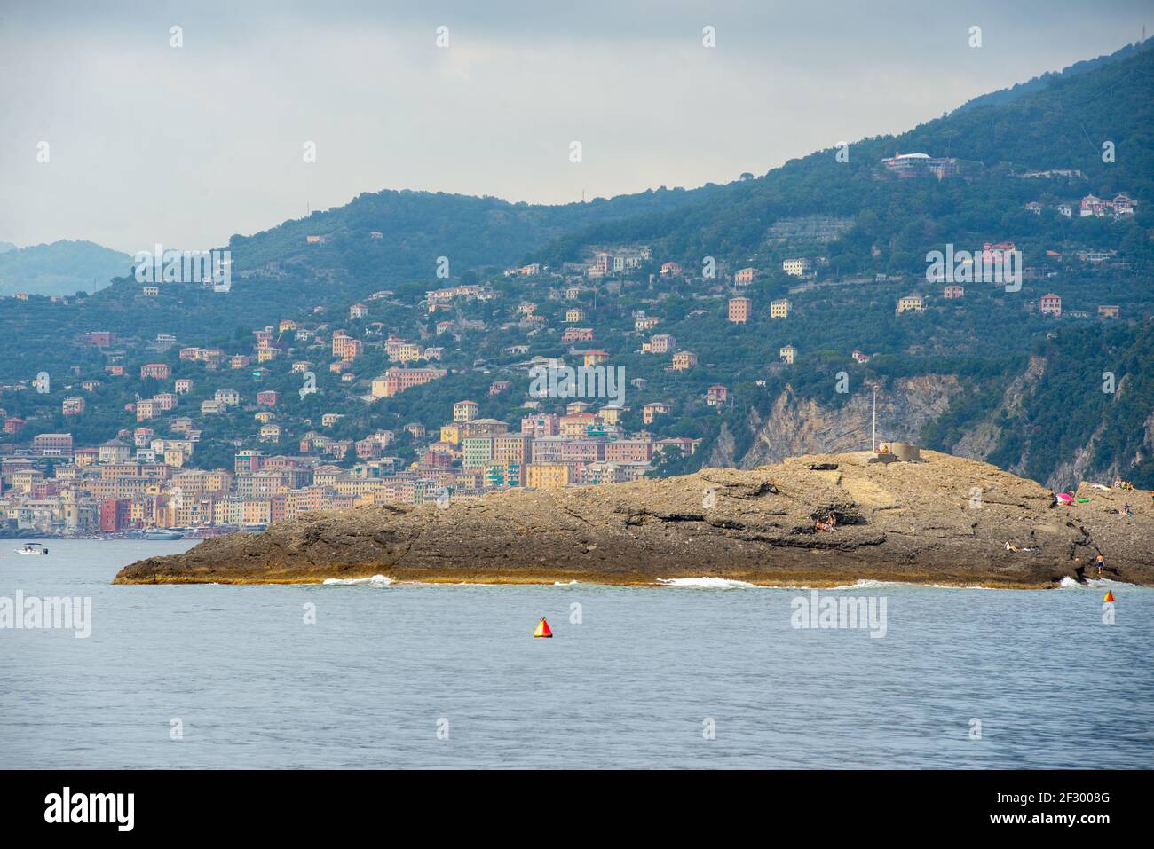 Der seltsame Felsen Punta Chiappa in der Nähe der Stadt Camogli kann nur mit dem Boot oder mit einer langen Wanderung erreicht werden. Camogli Stadt im Hintergrund Stockfoto