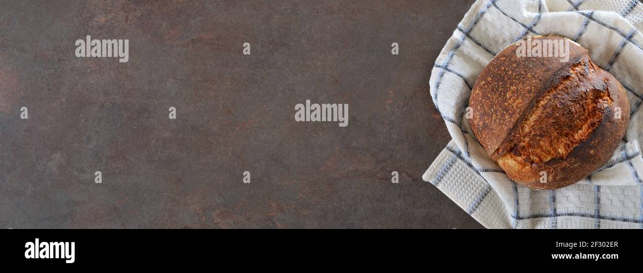Laib Roggenbrot auf einem Küchentuch auf dunklem Hintergrund. Layout mit Kopierbereich. Stockfoto