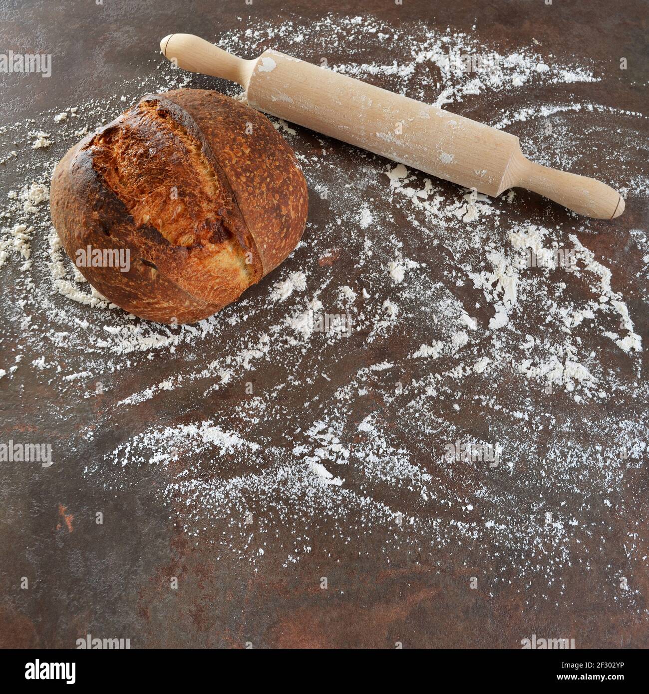 Hausgemachtes Sauerteig Brot mit einem Nudelholz auf dem Küchentisch mit Mehl bestreut. Stockfoto