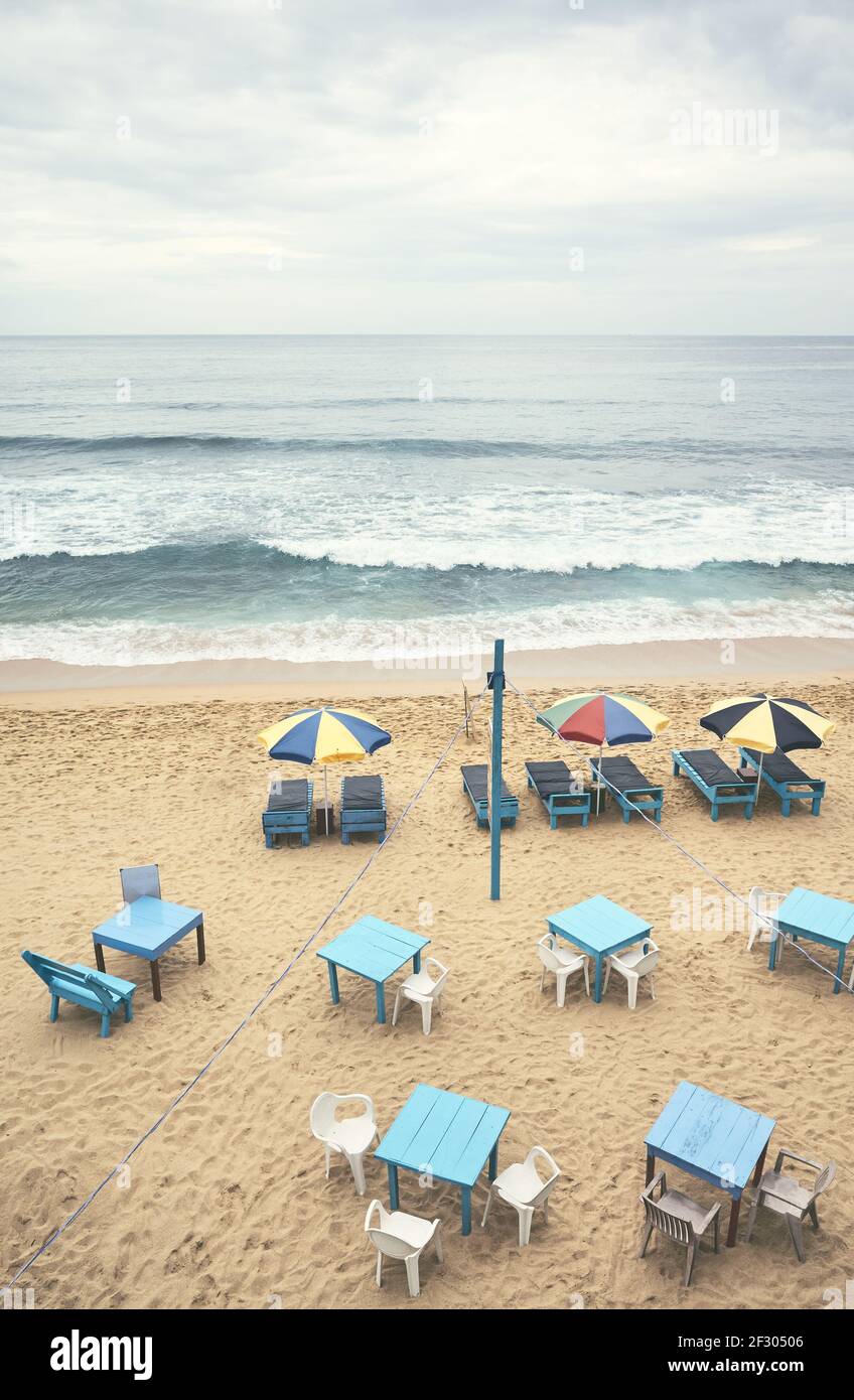 Luftaufnahme eines leeren tropischen Strandes mit Sonnenschirmen, Sonnenliegen, Tischen und Stühlen, Farbtonung angewendet, Sri Lanka. Stockfoto