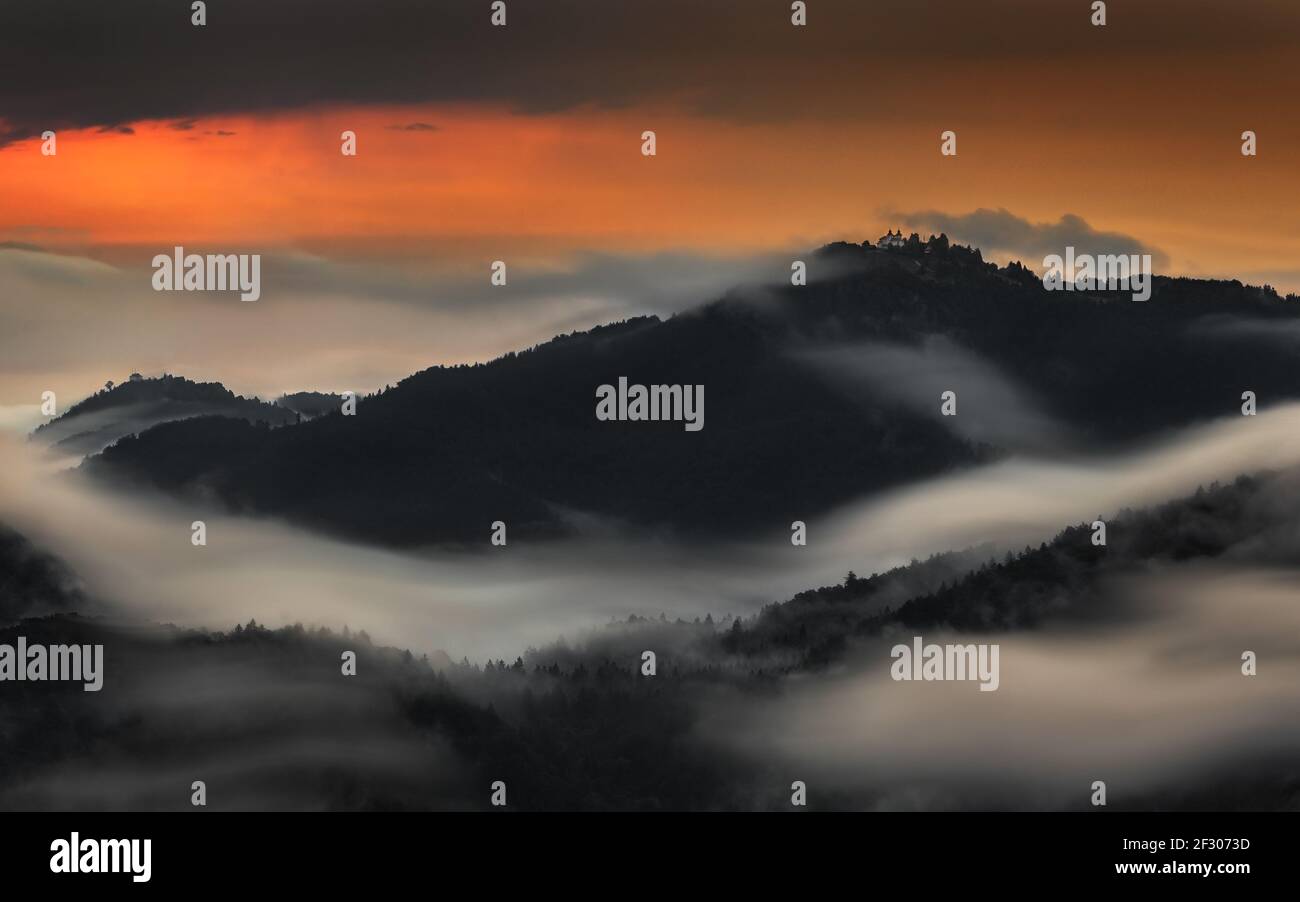 Skofja Loka, Slowenien - Langzeitbelichtung Panorama-Aufnahme der Berge der Region Kranj von Jamnik mit Sommermorgendnebel und goldenem Himmel bei Sonne aufgenommen Stockfoto