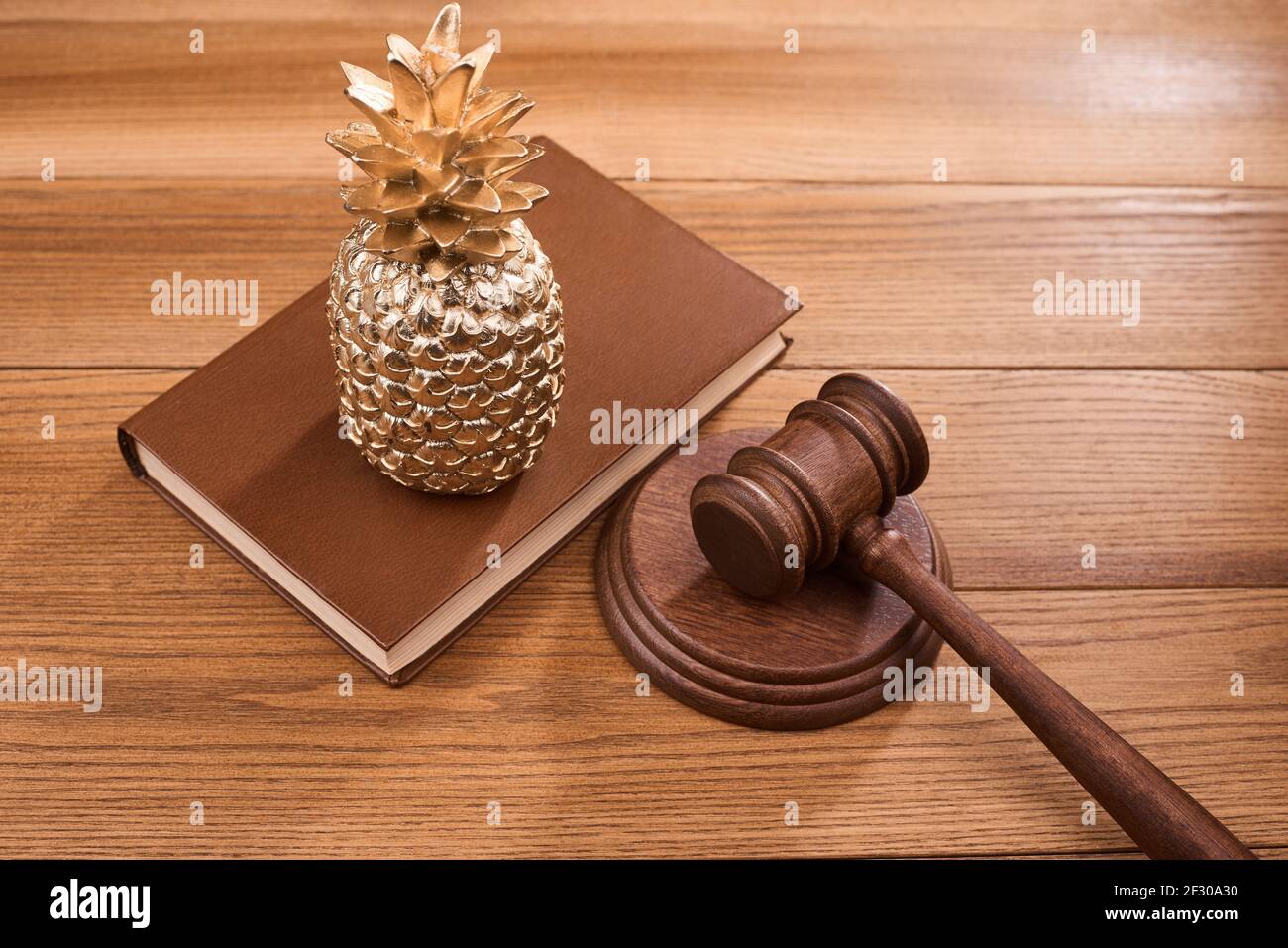 Eine goldene Zirbelkiefer, ein Richter s gavel und ein Gesetzbuch Stockfoto