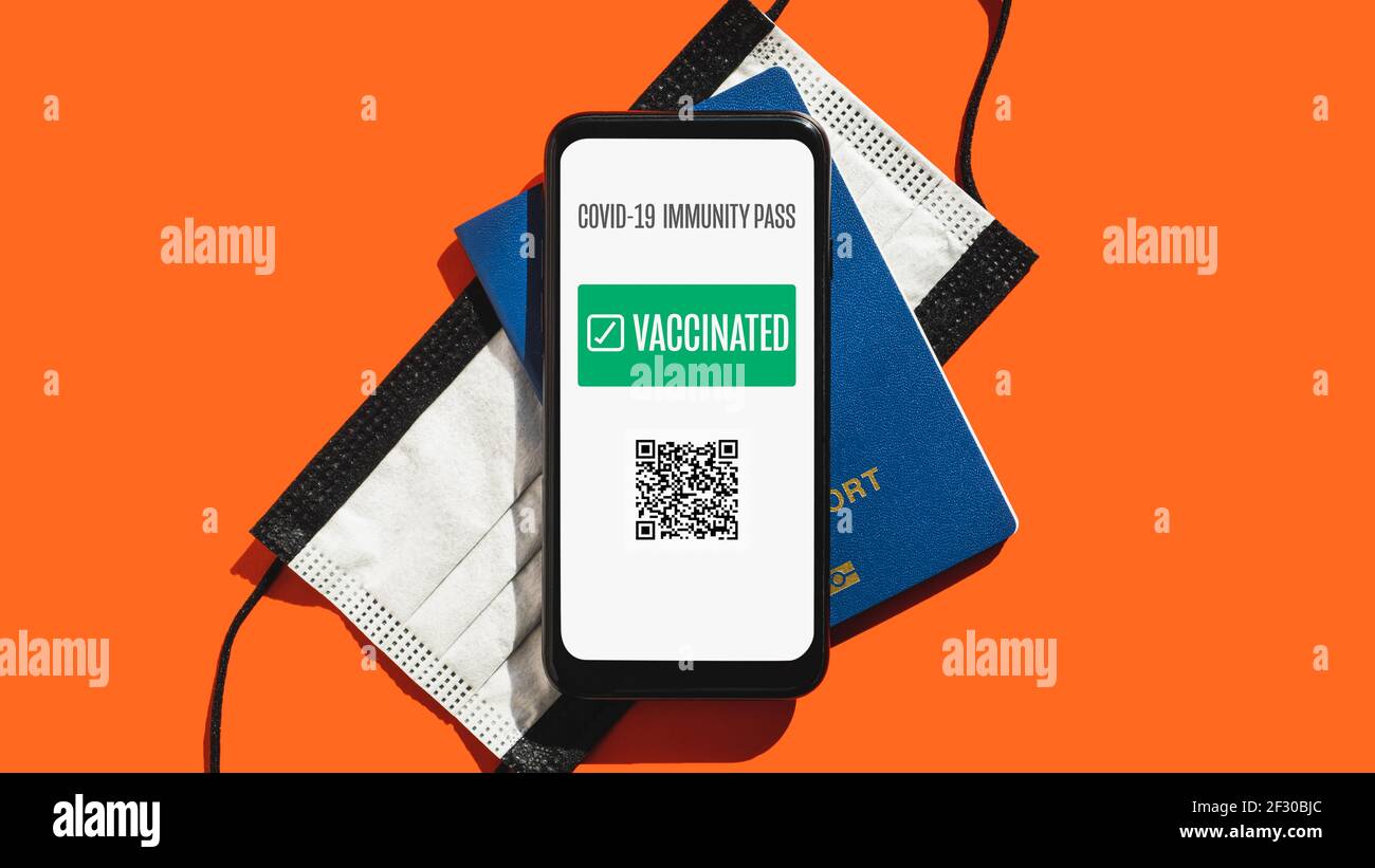 Post covid 19 Reisekonzept, digitales und Störfestigkeitsausweis Zertifikat. Telefonbildschirm mit geimpftem Schild, Gesichtsmaske und biometrischem Pass in hellem r Stockfoto