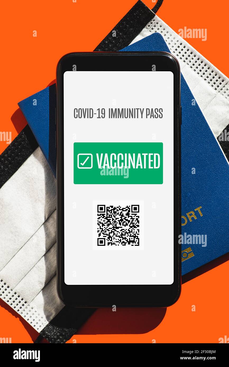 Post covid 19 Reisekonzept, digitales und Störfestigkeitsausweis Zertifikat. Telefonbildschirm mit geimpftem Schild, Gesichtsmaske und biometrischem Pass in hellem r Stockfoto
