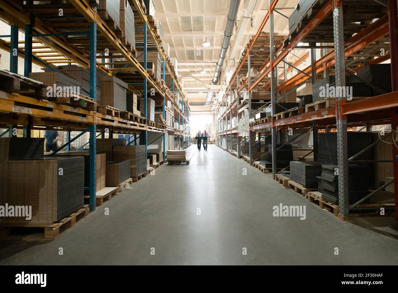 Nicht erkennbare Arbeiter, die im Lager in der Fabrik herumlaufen Stockfoto
