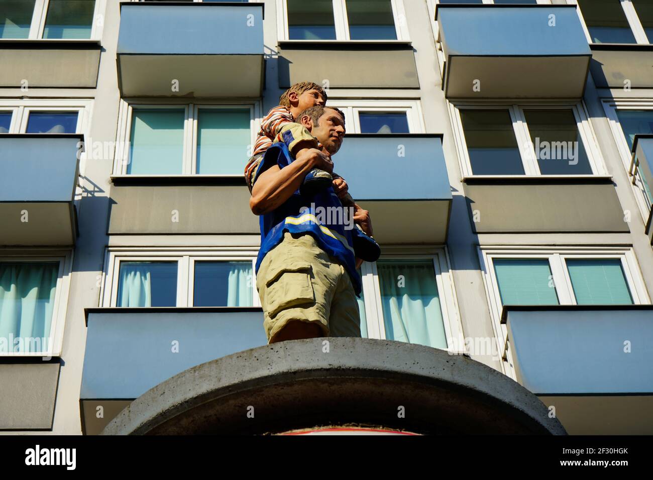 Säulenheilige von Christoph Pöggeler: Lebensechte Skulpturen von alltäglichen Menschen, die auf Werbesäulen stehen. Dieser wird 'Vater und Sohn' genannt. Stockfoto