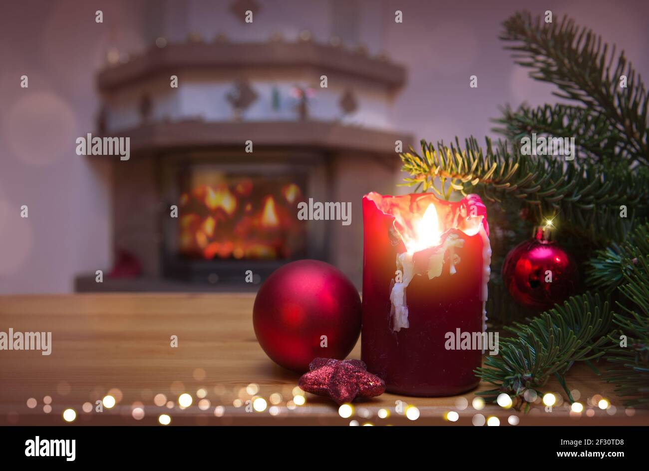 Weihnachtshintergrund mit brennender Kerze, Kamin und geschmücktem Weihnachtsbaum Stockfoto