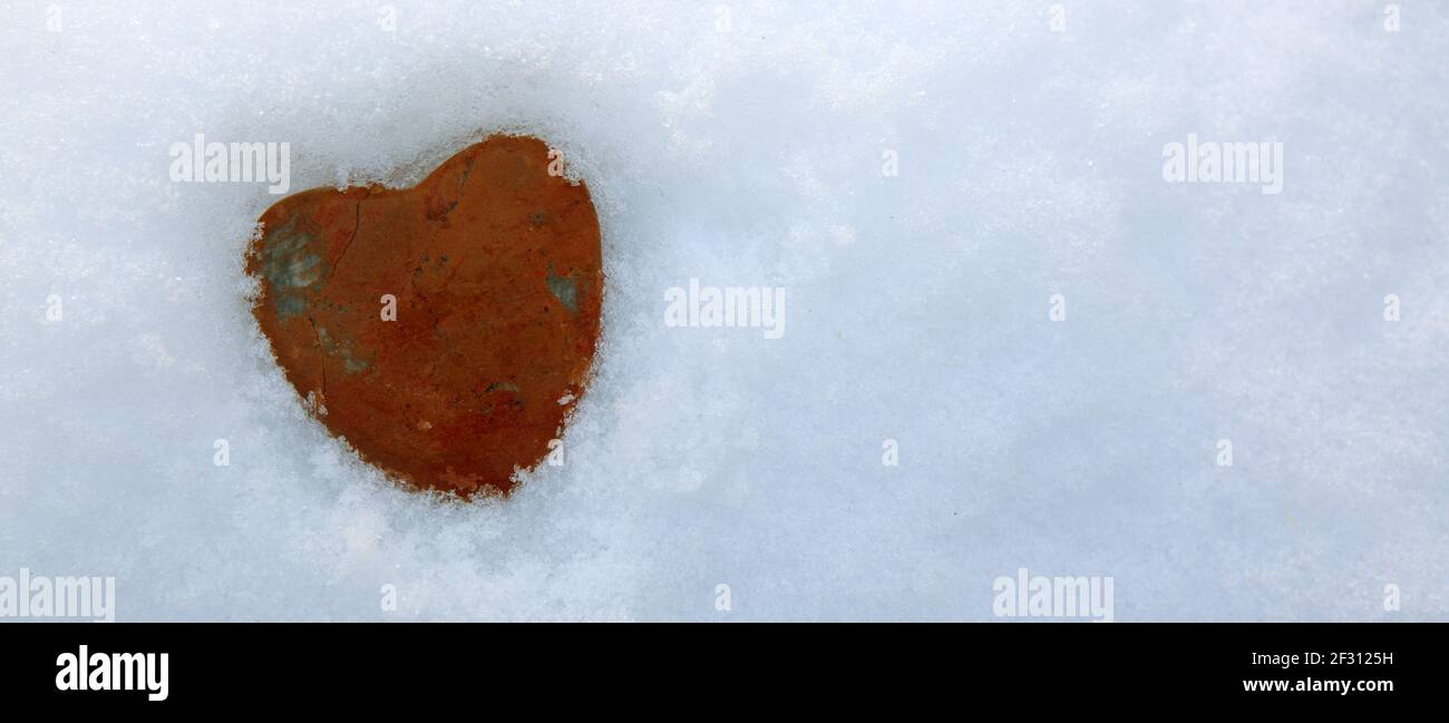 Herz aus rotem Stein in weißem Schnee.Valentinstag Hintergrund. Stockfoto