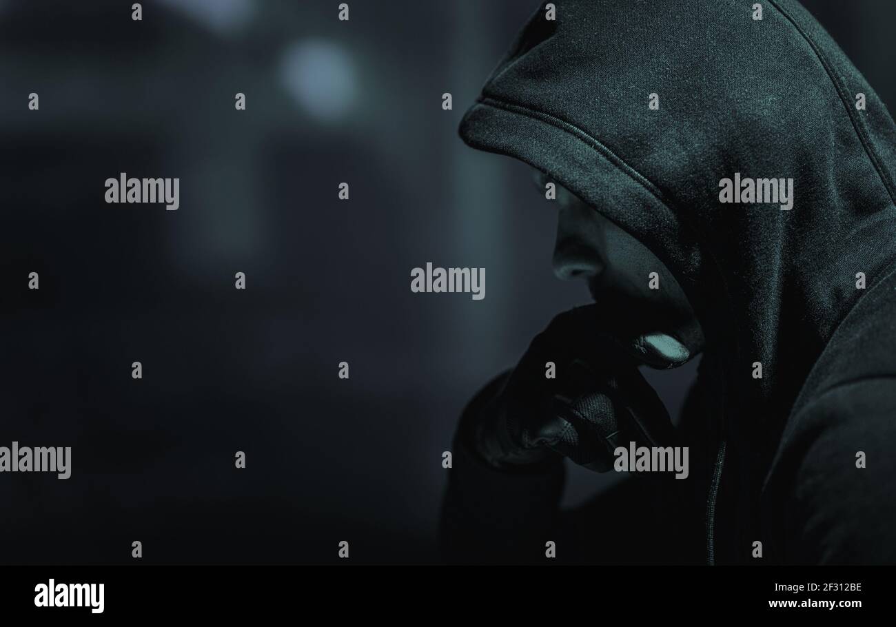 Verdächtige kaukasische Männer in seinem 30s trägt schwarzen Hoodie und taktische Handschuhe. Stockfoto