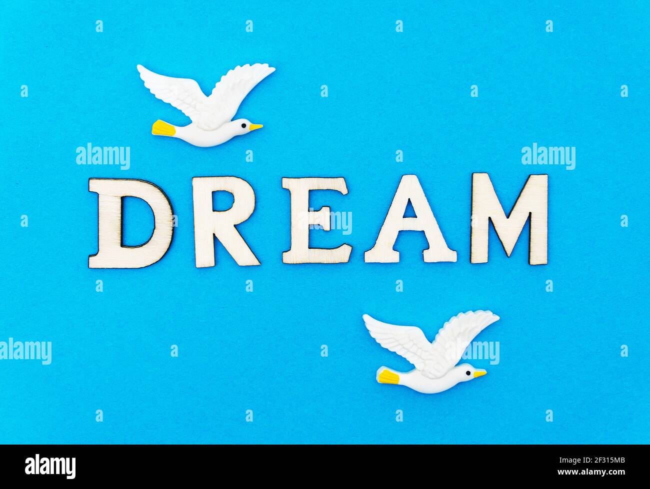 WORTTRAUM und zwei weiße Plastikmöwen auf blauem Hintergrund. Traumkonzept Sommerurlaub. Stockfoto