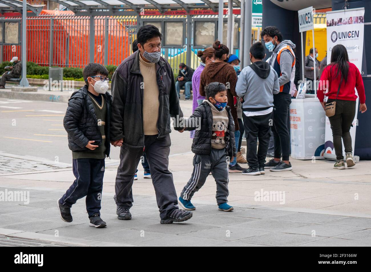 El Alto, La Paz, Bolivien - Februar 11 2021: Der indigene Mann Boliviens geht mit jeder Hand und hält sein Kind, alle tragen eine Maske Stockfoto