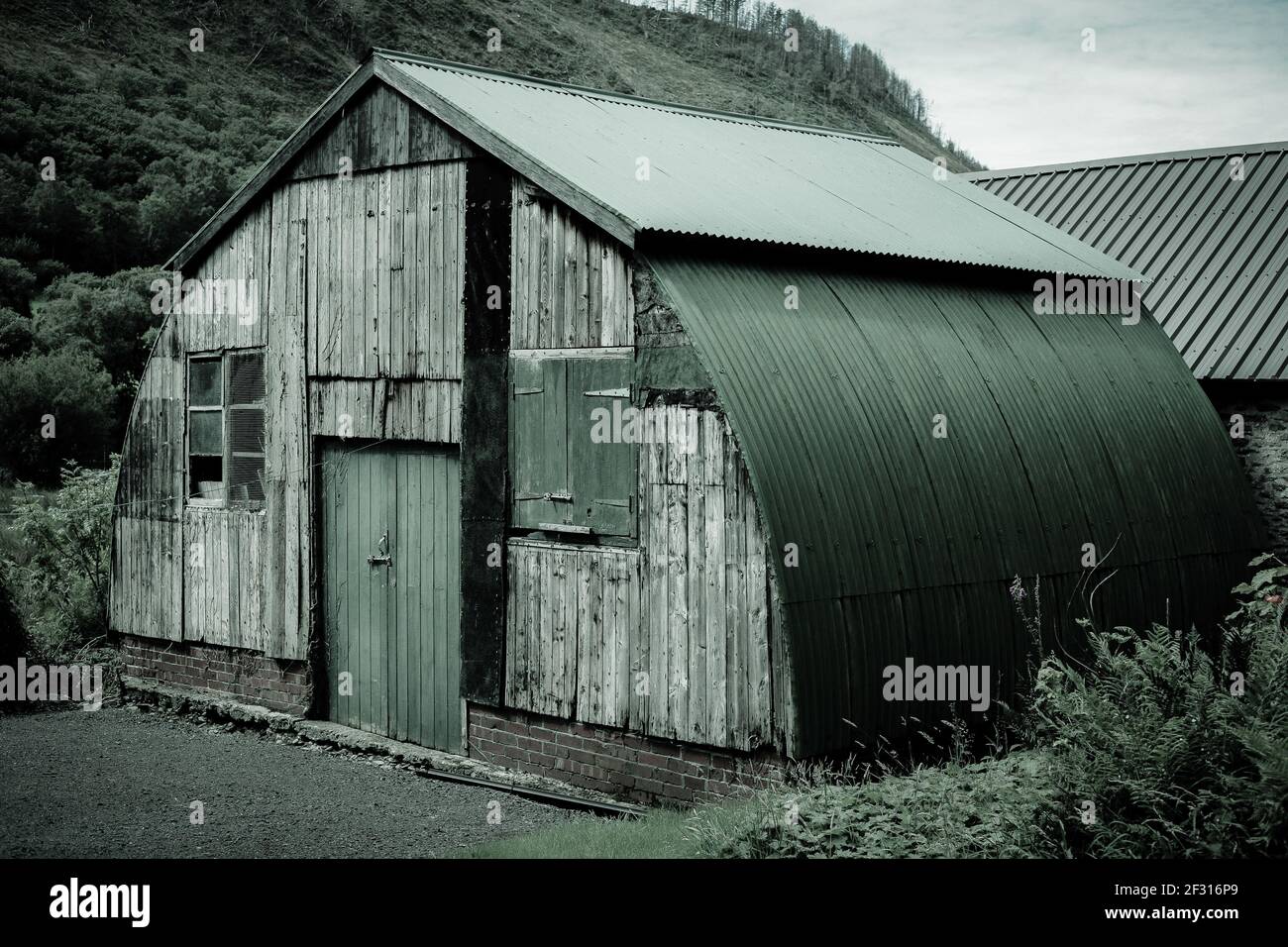 Ein alter, grüner, gewellter Schuppen, schön geschwungen. Gelegen im Rheidol Valley, Wales. Eine rustikale, handgefertigte Konstruktion. Stockfoto
