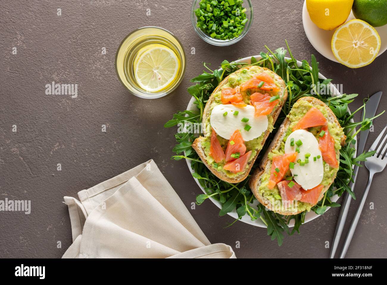 Leckeres herzhaftes Frühstück, Sandwiches mit Avocado-Paste, Lachs und Mozzarella auf einem Teller mit Rucola und Erbsensprossen Stockfoto