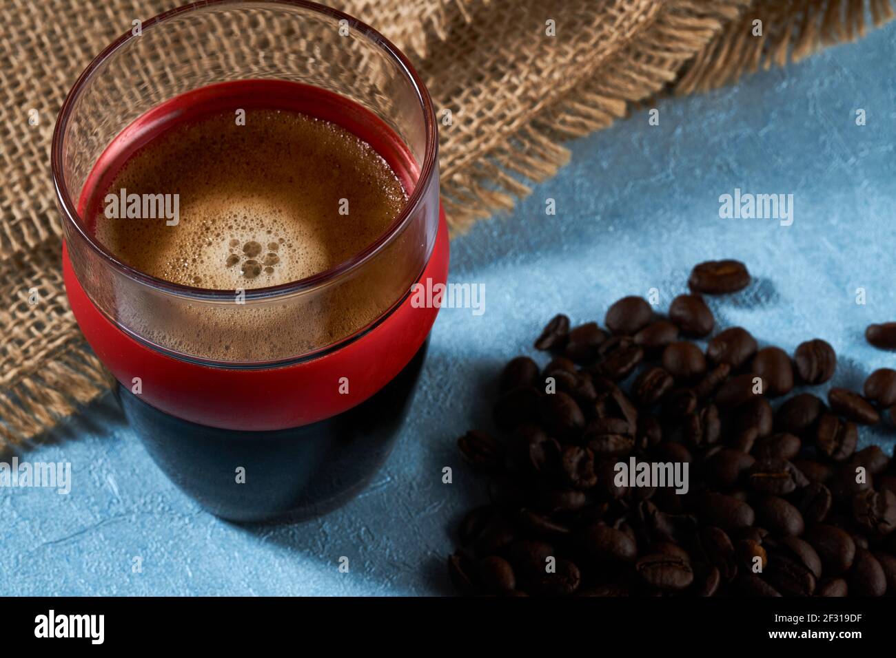 Kleines Glas auf der Seite mit Kaffeebohnen und Sacktuch. Stockfoto