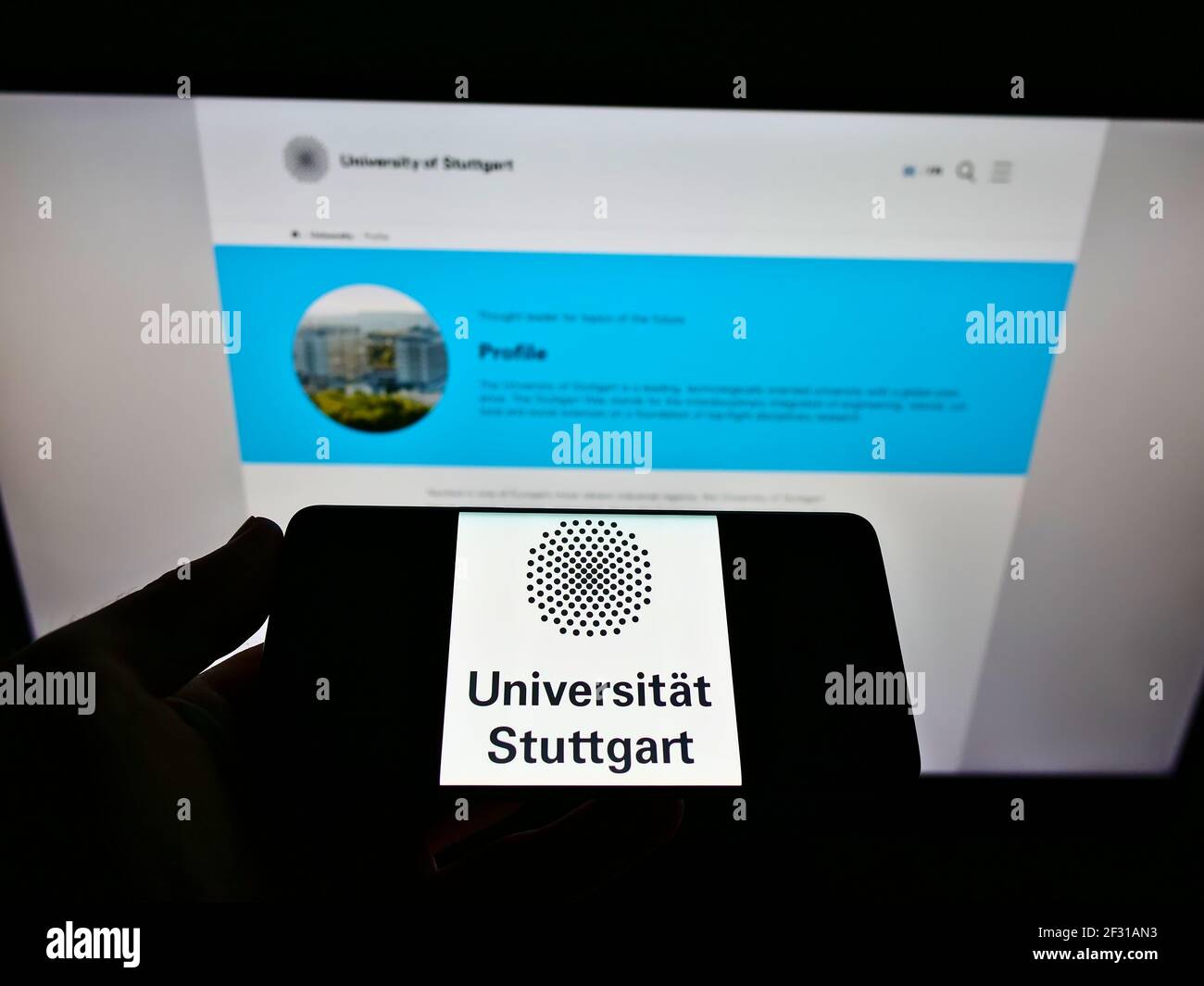 Person mit Mobiltelefon mit Logo der deutschen Bildungseinrichtung Universität Stuttgart auf dem Bildschirm vor der Webseite. Konzentrieren Sie sich auf die Telefonanzeige. Stockfoto