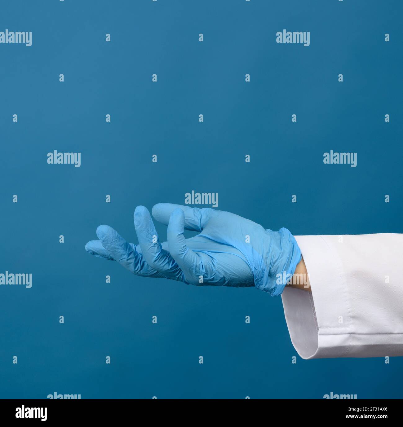 Weibliche Hand in blauen Latexhandschuhen auf blauem Hintergrund Stockfoto