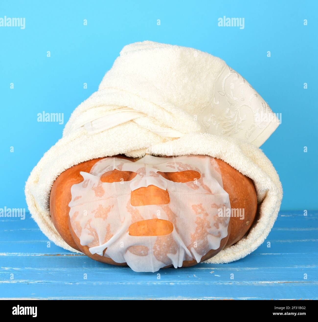 Runder, orangefarbener Kürbis, umhüllt von einem weißen Frottee Stockfoto