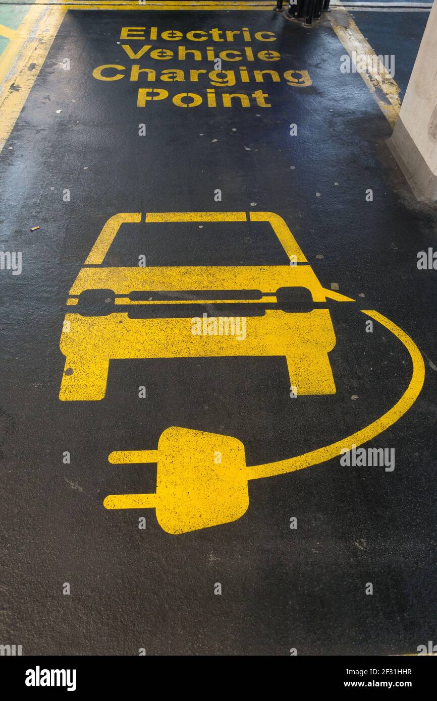 Linienmarkierungen in einer Parkbucht in gelb auf schwarzem Asphalt eines Autos und elektrischer Ladeleitung sind sichtbar. Stockfoto