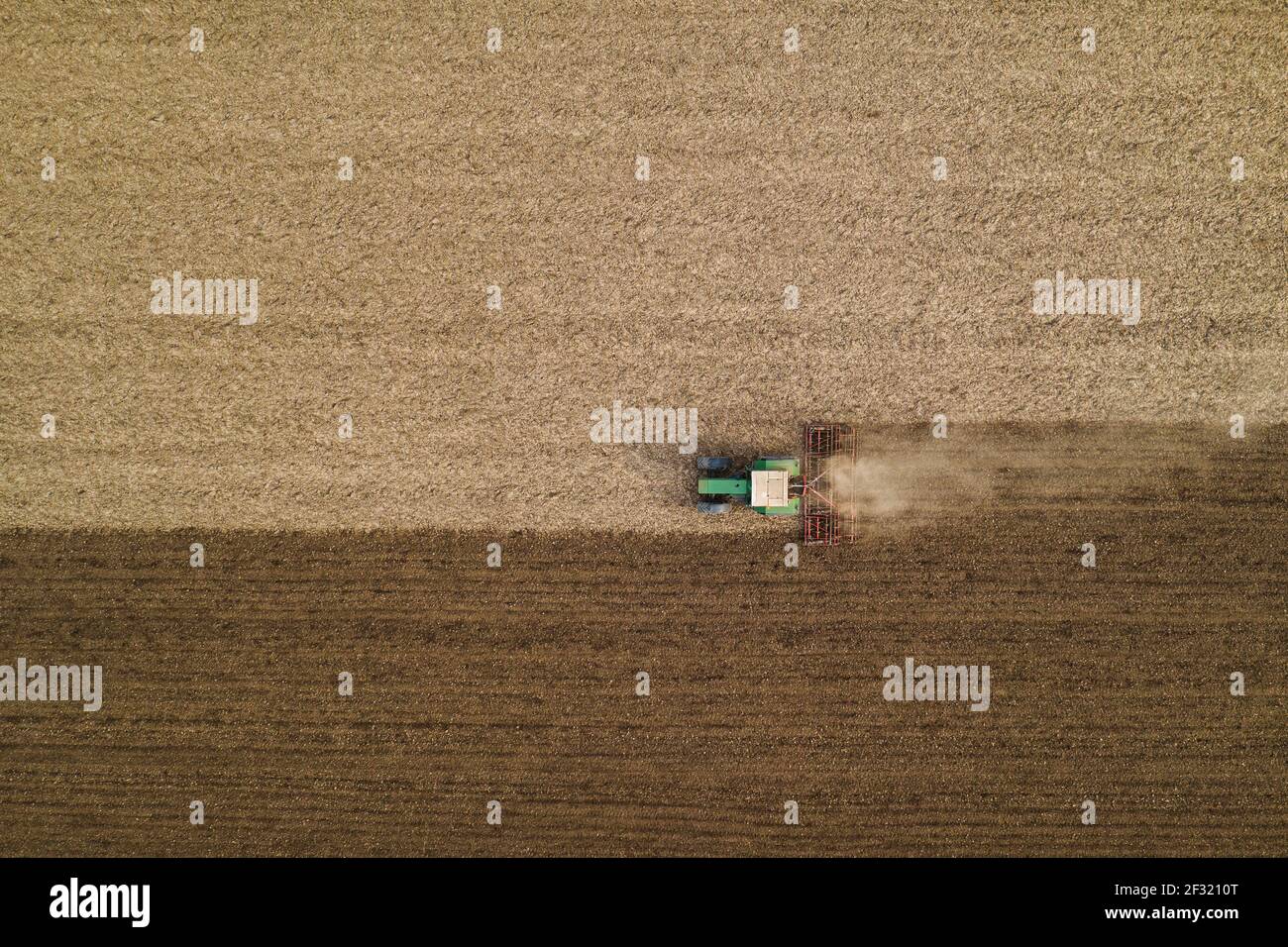 Luftaufnahme der landwirtschaftlichen Traktor Bodenbearbeitung und erschütternde gepflügten Feld, direkt über Drohne pov Bild von Maschinen arbeiten auf Ackerland Stockfoto