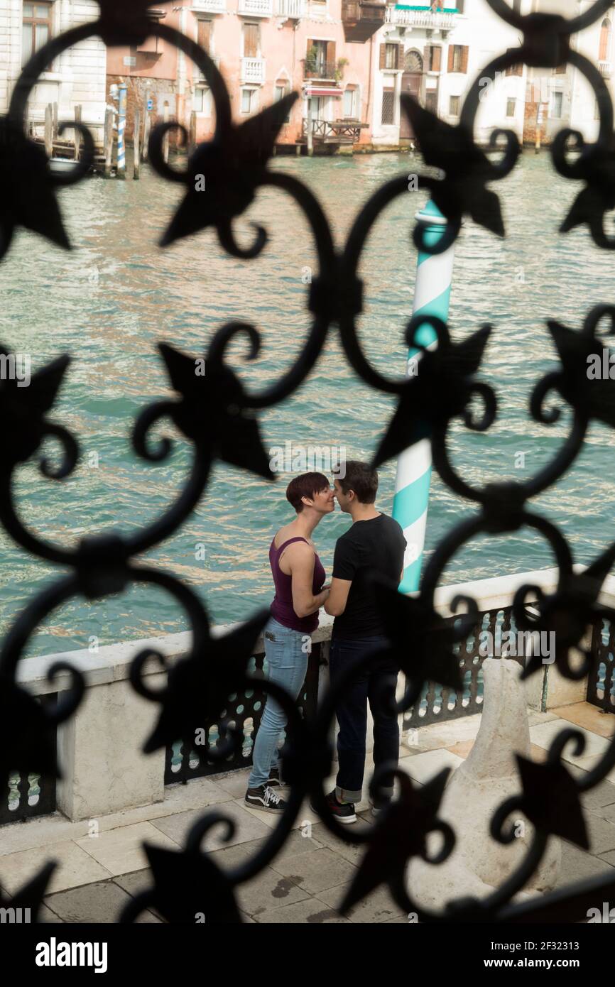 Italien, Venedig, ein Paar, das sich küsst, als es durch einen Metallfensterschirm betrachtet wird Stockfoto