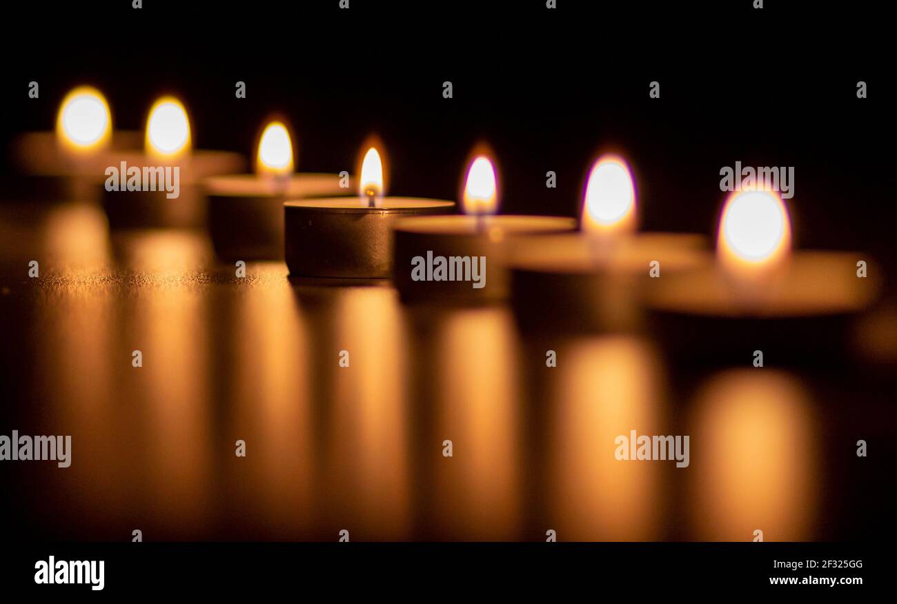 Nahaufnahme von vielen brennenden Kerzen. Das Kerzenlicht wird reflektiert. Stockfoto