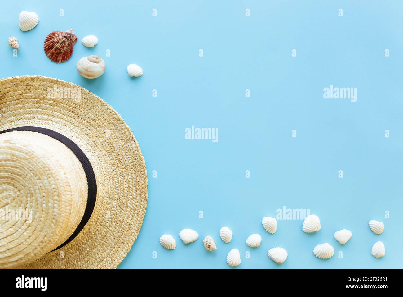 Reise- oder Urlaubskonzept. Hut mit Muscheln. Entspannung. Blauer Hintergrund. Hochwertige Fotos Stockfoto