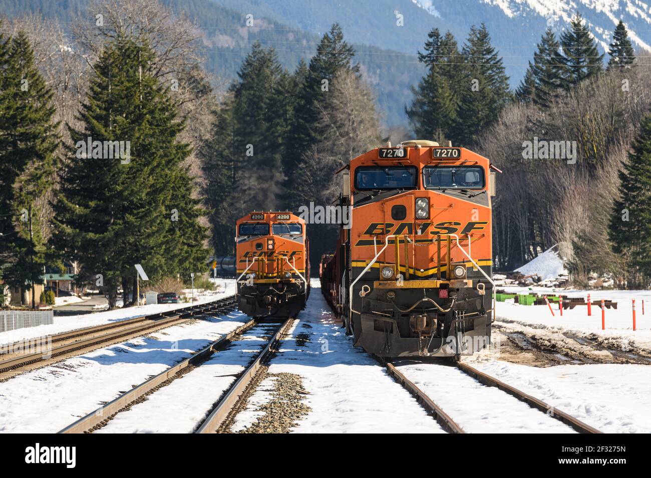 Zwei BNSF-Güterzüge in Skykomish in Washington Kaskadiert Berge, während der Winterschnee schmilzt Stockfoto