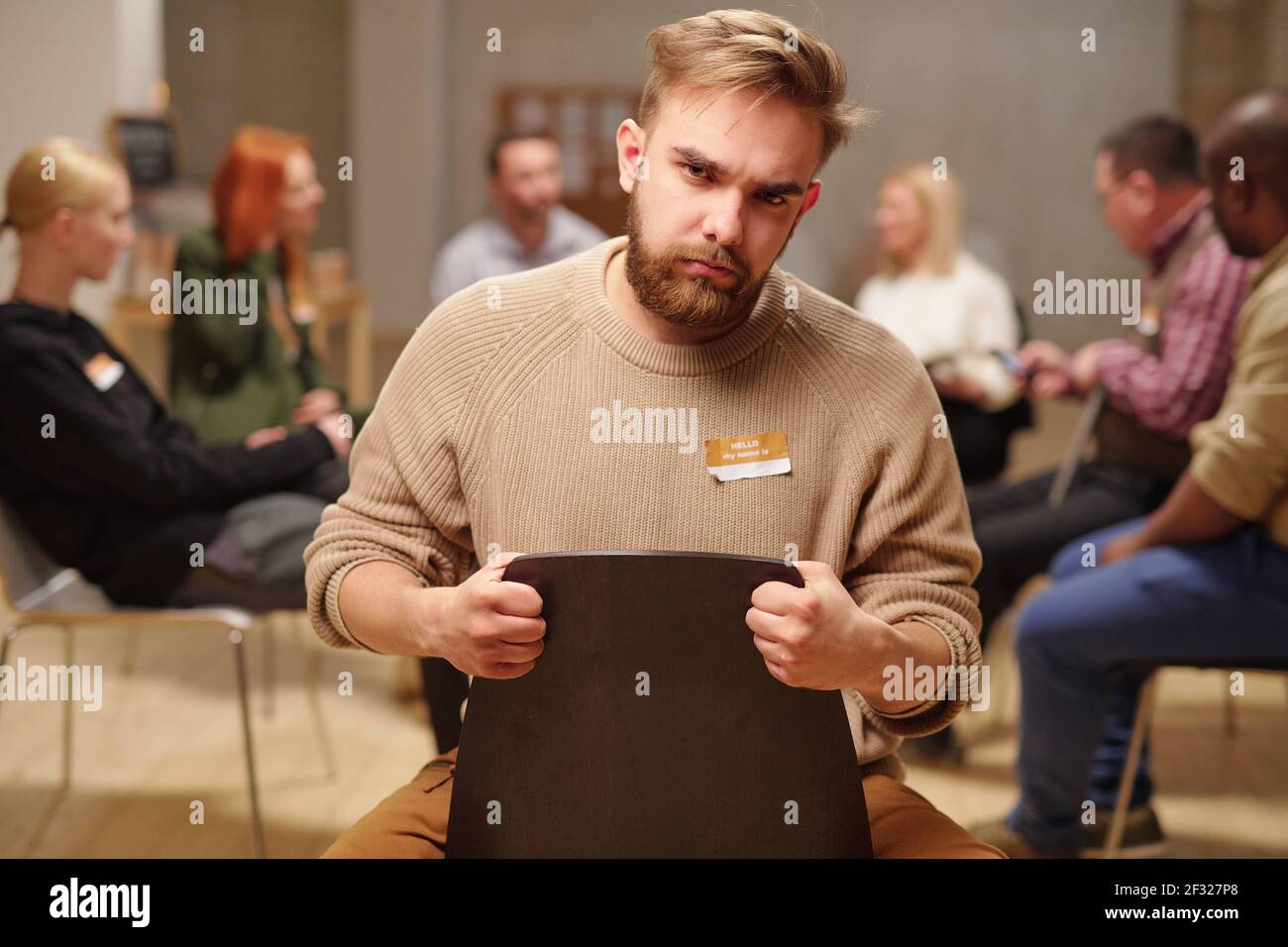 Ernster und runzeliger Mann, der dich anschaut, während er gegen dich sitzt Mentale Unterstützung Gruppe mit Diskussion von Problemen während der Sitzung Stockfoto