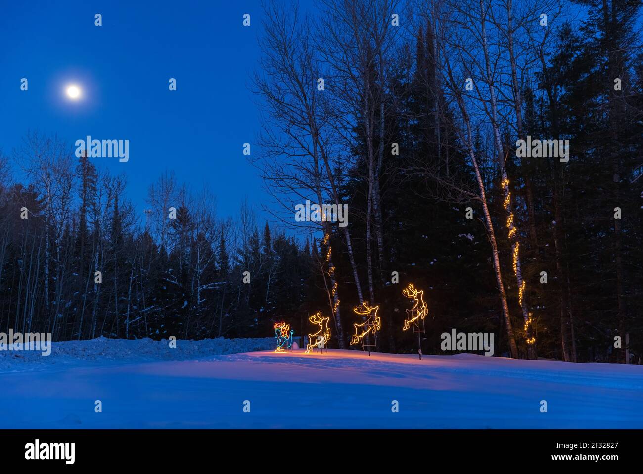 Das blaue Licht der Dämmerung, ein Vollmond und Feiertagsdekorationen im nördlichen Wisconsin. Stockfoto