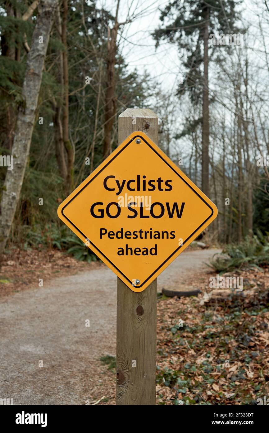 Radfahrer gehen langsam Fußgänger voraus Schild auf einem Weg im Pacific Spirit Regional Park, Vancouver, British Columbia, Kanada Stockfoto