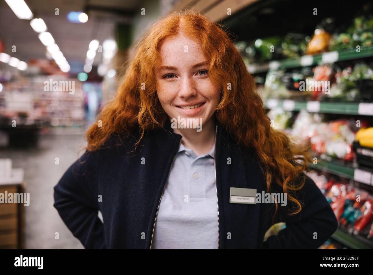 Portrait eines jungen Supermarktangestellten. Frau auf einem Ferienjob in einem Lebensmittelgeschäft. Stockfoto