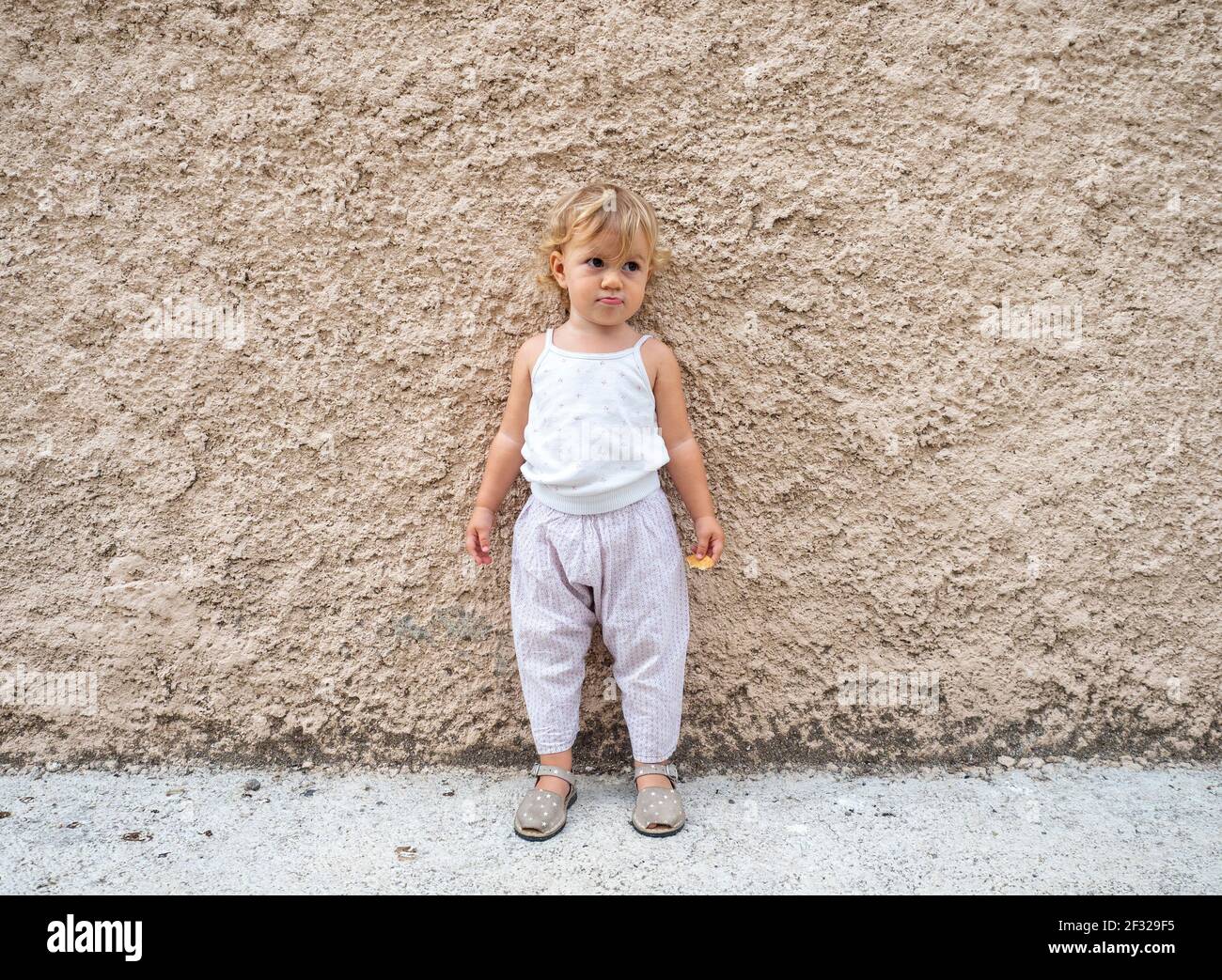 Baby Mädchen im Sommer agaisnt eine Wand Stockfoto