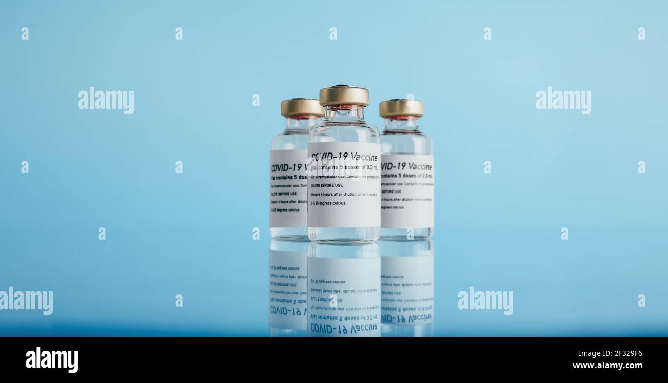 Coronavirus-Impfstoff. Drei Fläschchen mit Impfstoff auf blauem Hintergrund. Stockfoto