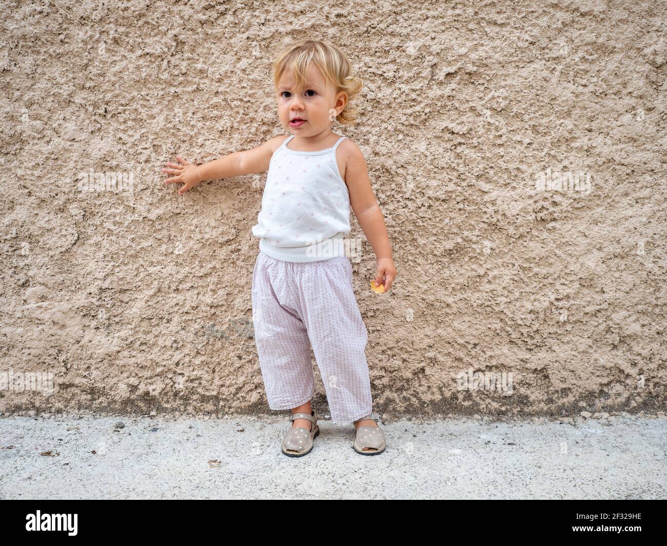 Baby Mädchen im Sommer agaisnt eine Wand Stockfoto