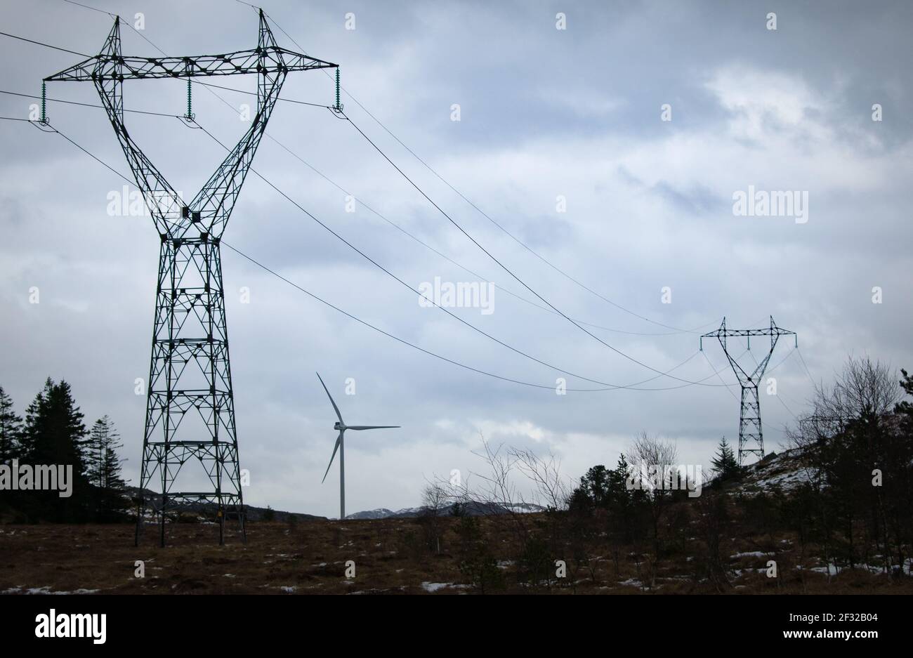 Windmühle neben Stromleitungen während der Winterzeit in Norwegen. Konzept für saubere Energie Stockfoto