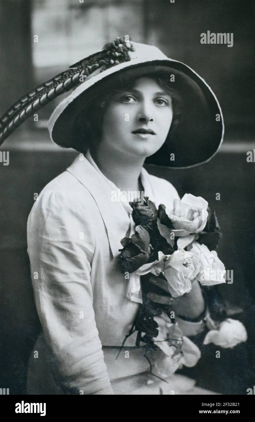 Die berühmte edwardianische englische Bühne und später der Film, die Schauspielerin Gladys Cooper (1888-1971), die einen Hut trägt und einen Strauß Rosen in der Hand hält, aufgenommen von einer Fotopostkarte aus dieser Zeit. Stockfoto