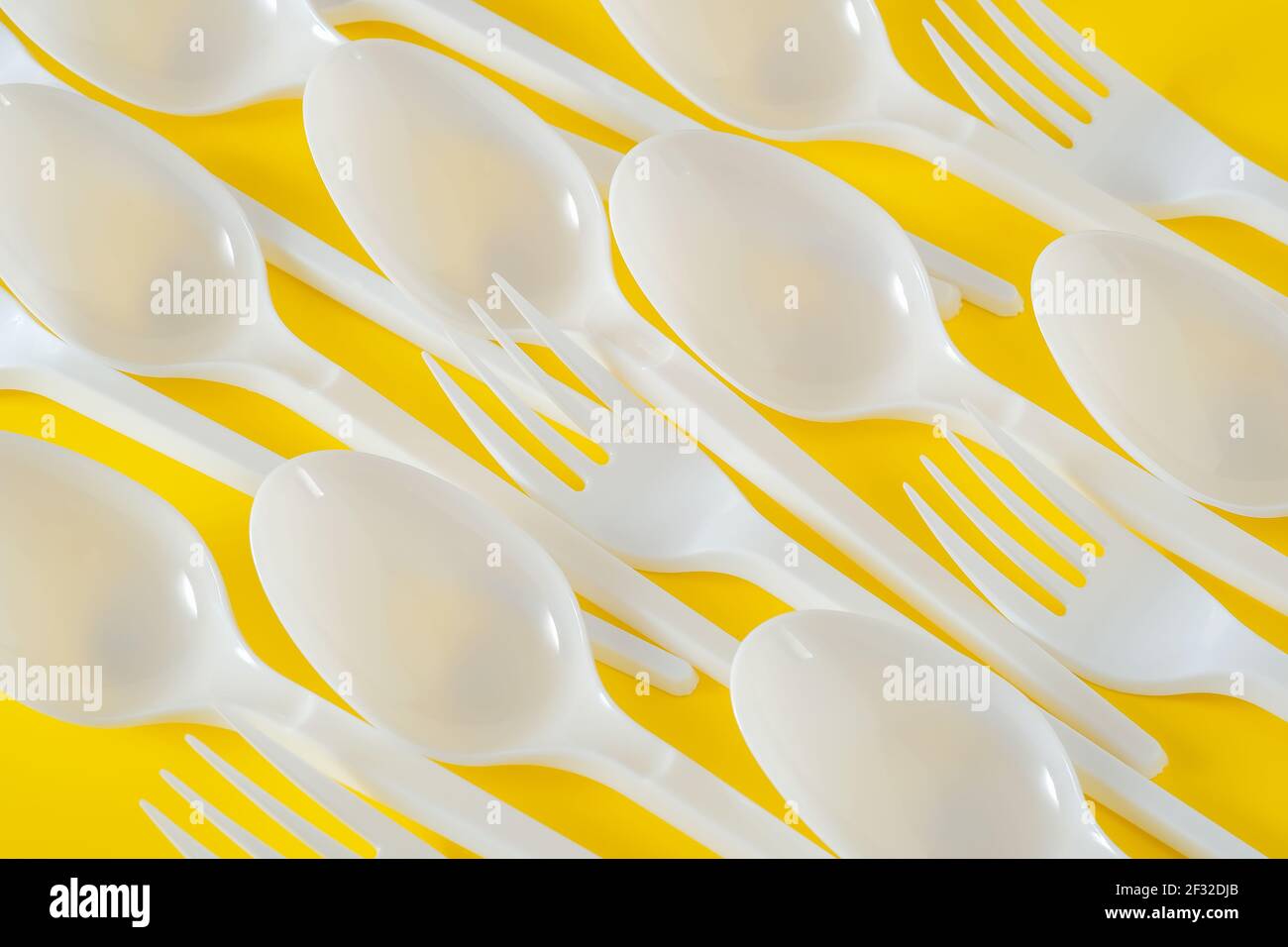 Plastiklöffel und Gabeln auf gelbem Hintergrund Stockfoto