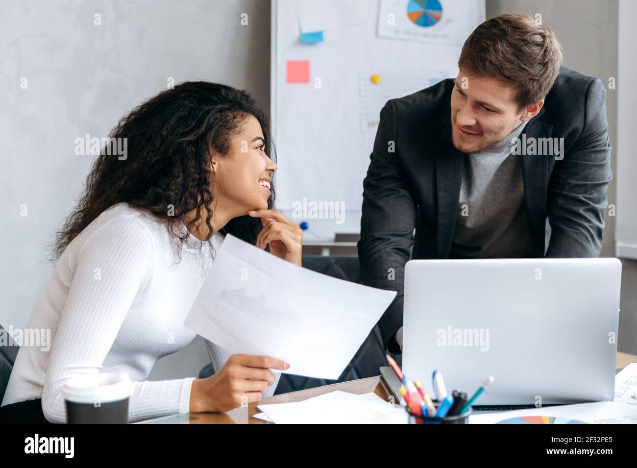 Erfolgreiche Geschäftspartner arbeiten gemeinsam an neuen Projekten im modernen Büro. Multirassische männliche und weibliche Kollegen auf Briefing-Meeting diskutieren Ideen, Papierkram zu tun Stockfoto