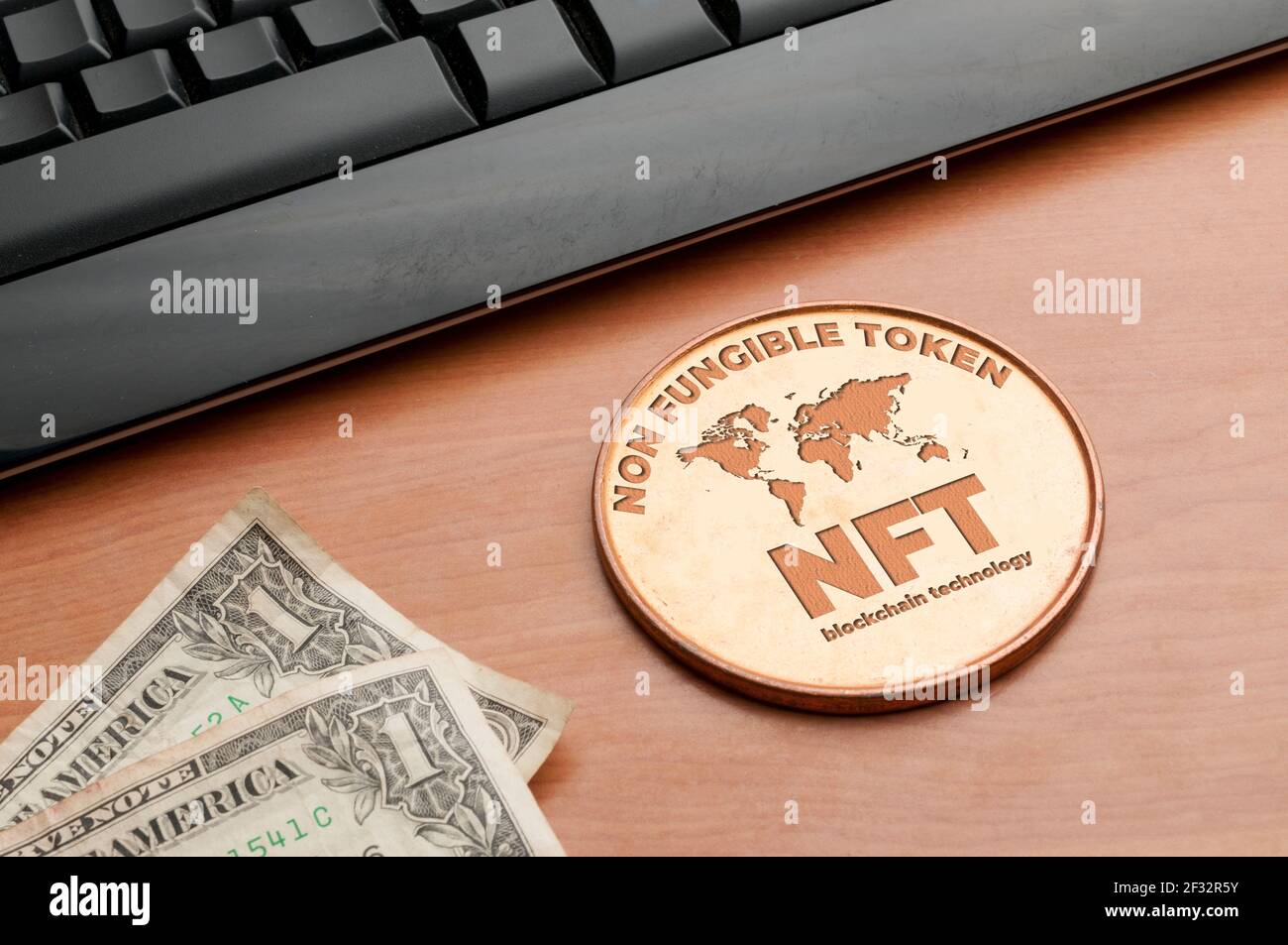 NFT (non fungible Token) Konzept: Große Kupfermünze auf einem Holztisch mit Computertastatur und zwei Dollarscheinen Stockfoto