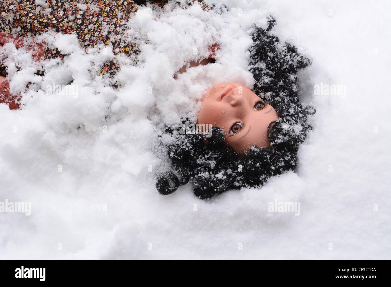 Mädchen Puppe mit schwarzen lockigen Haaren immer von Schnee begraben Im Schneesturm Stockfoto