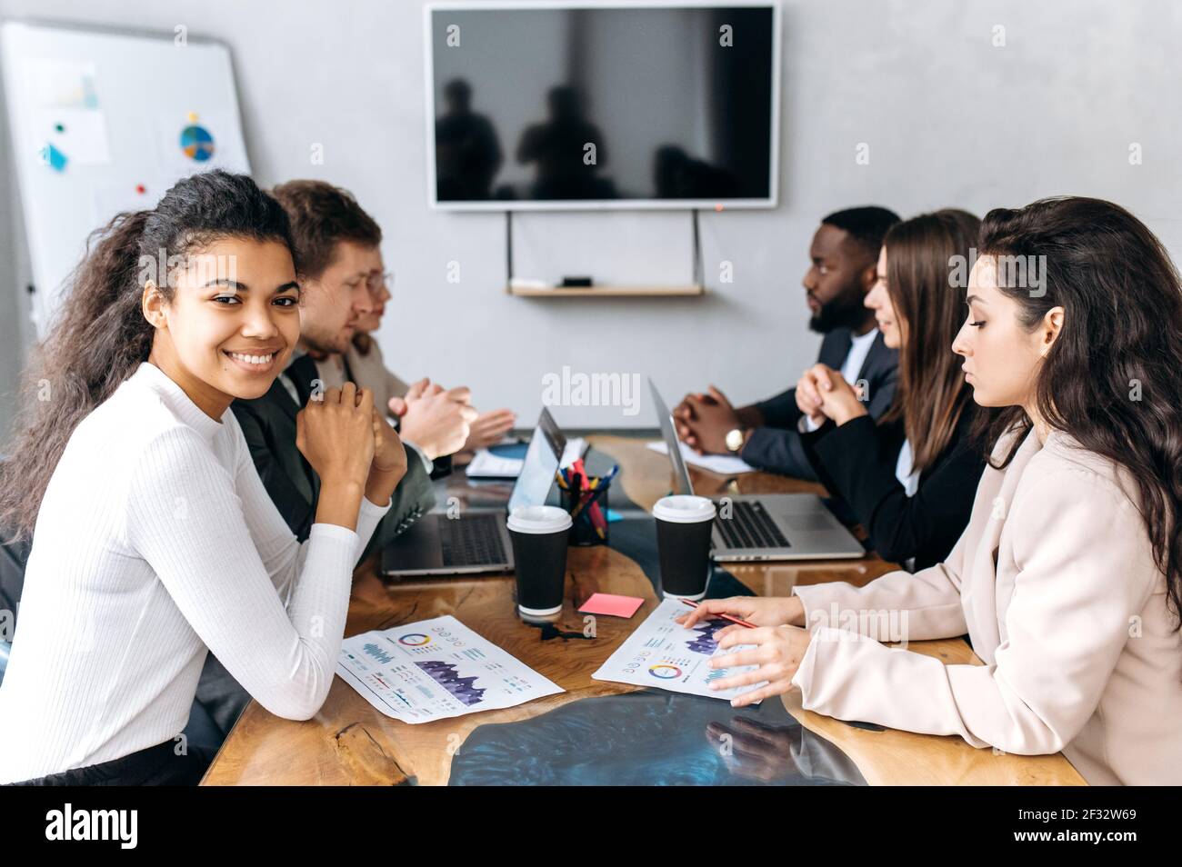 Erfolgreiche Gruppe von Geschäftsleuten auf der Konferenz, Diskussion Projekt. Multirassische Mitarbeiter in formellen Anzügen, die Finanzdiagramme betrachten, gemeinsam Brainstorming durchführen, an einem neuen Start-up arbeiten Stockfoto