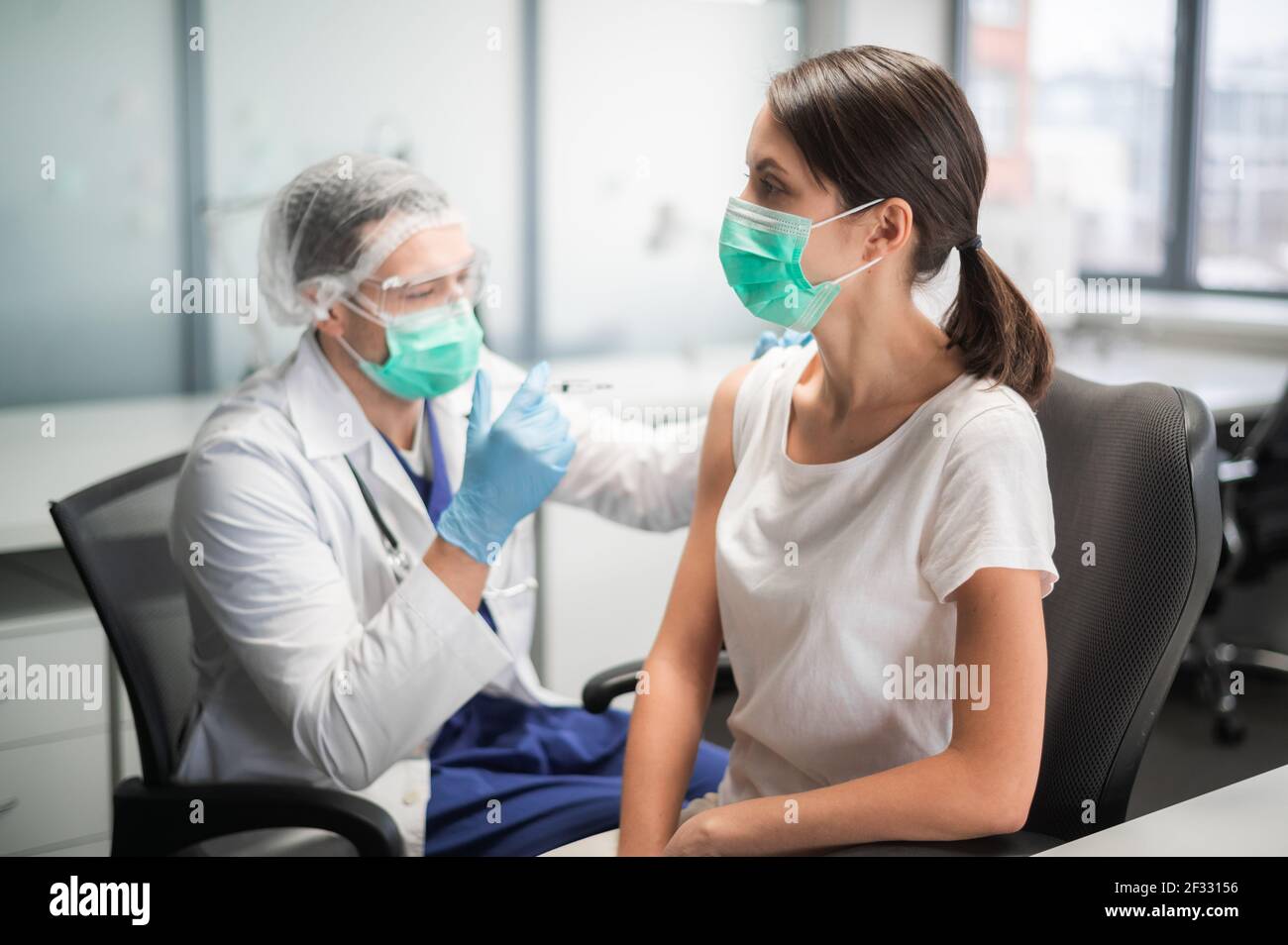 In einem medizinischen Labor wird eine junge Frau während einer Pandemie gegen Coronavirus geimpft Stockfoto