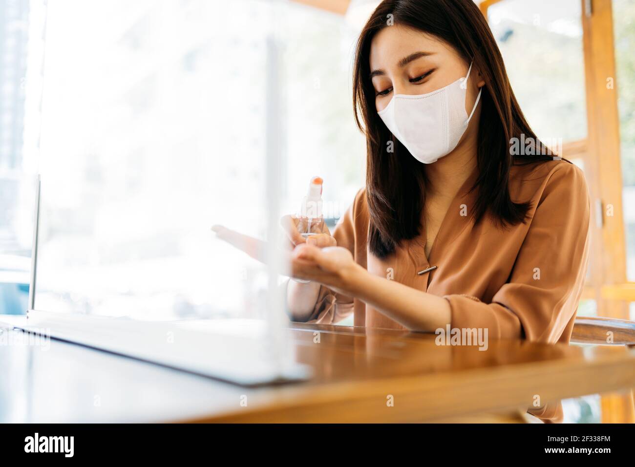 Junge schöne asiatische Frau trägt covid-19 Schutz Gesichtsmaske Anwendung Medizinisches Händedesinfektionsmittel für Sicherheit und Vorsorge gegen Coronavirus-Viren Stockfoto