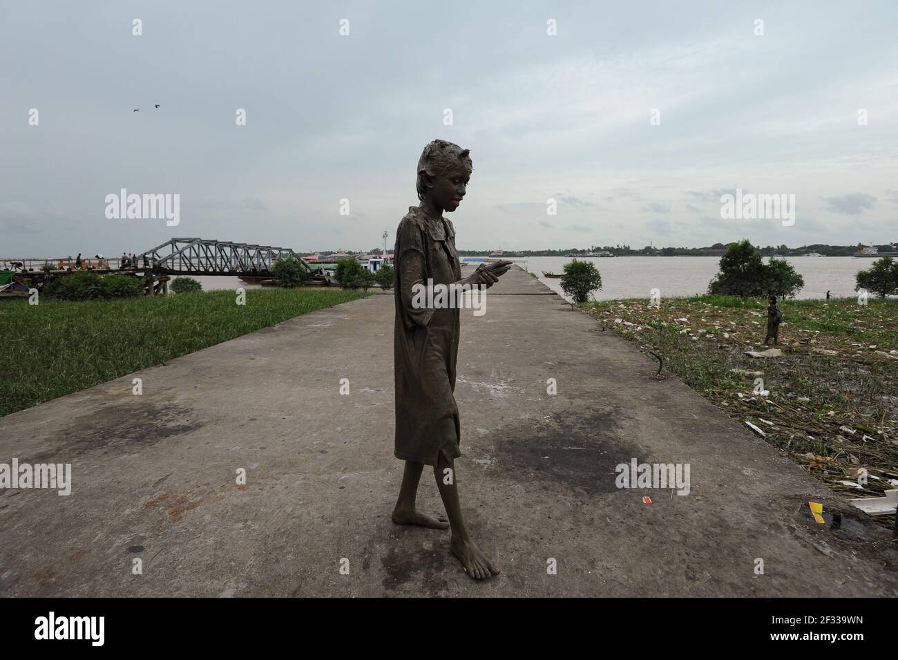 22,08.2013, Yangon, Myanmar, Asien - Porträt eines einheimischen Mädchens, dessen Gesicht und Körper von Kopf bis Fuß mit natürlichem Schlamm aus dem Yangon-Fluss bedeckt sind. Stockfoto