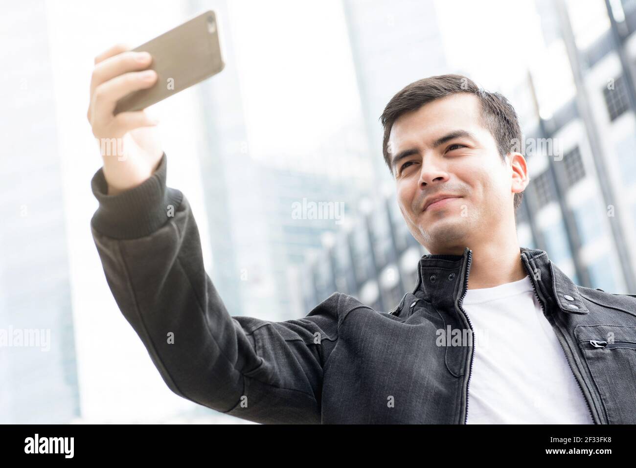 Junger Mann nimmt Selfie in der Stadt mit dem Smartphone Stockfoto