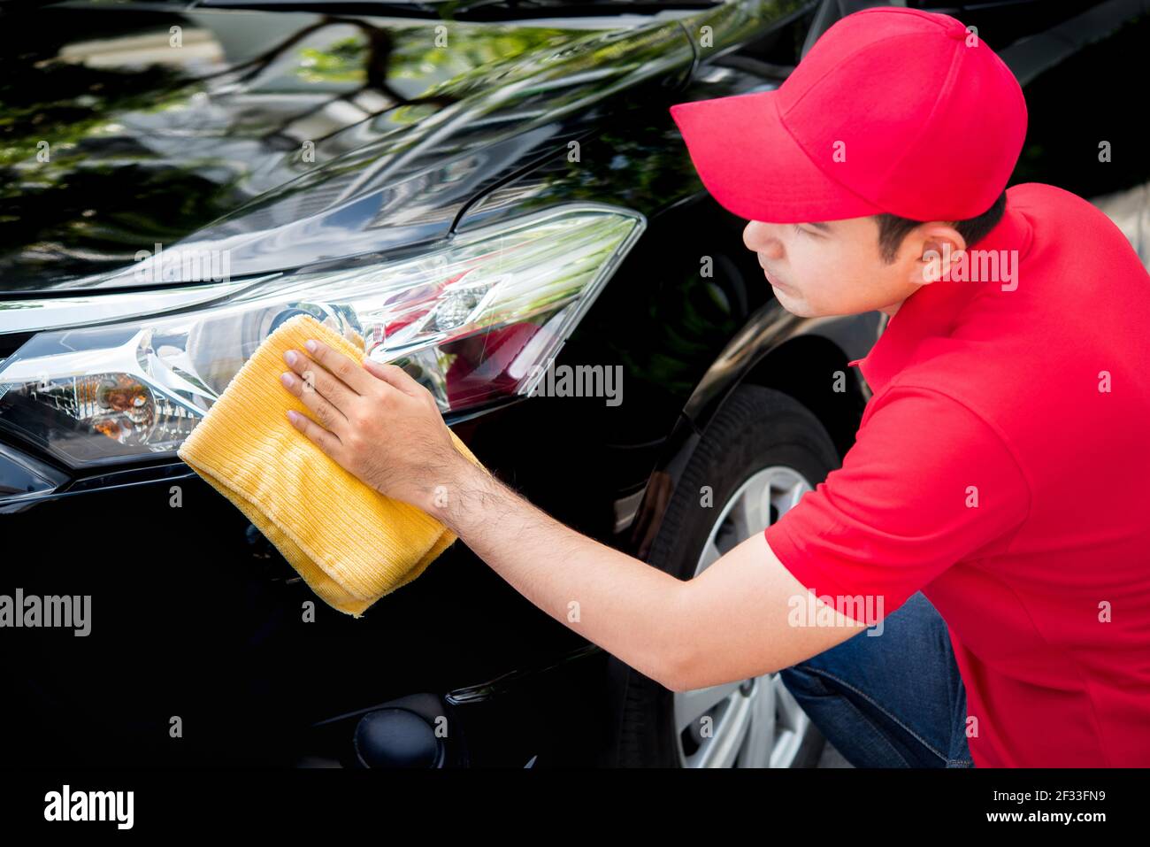 Auto-Service-Personal in roten Uniform Reinigung Auto mit Mikrofaser Tuch - Auto Detaillierung und Valeting Konzepte Stockfoto