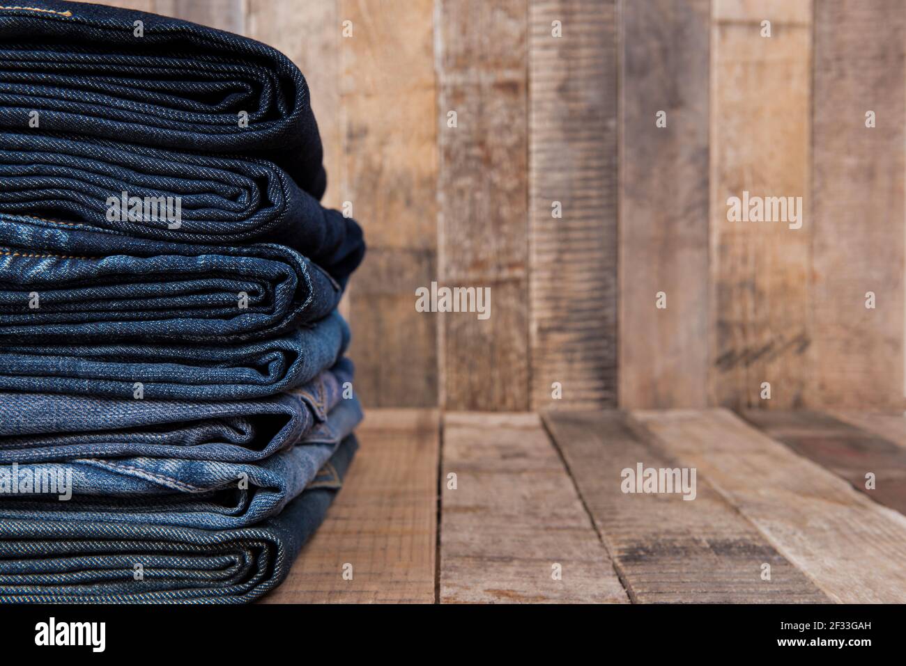 Stapel blauer Jeans auf altem Holzhintergrund mit Kopie Platz Stockfoto