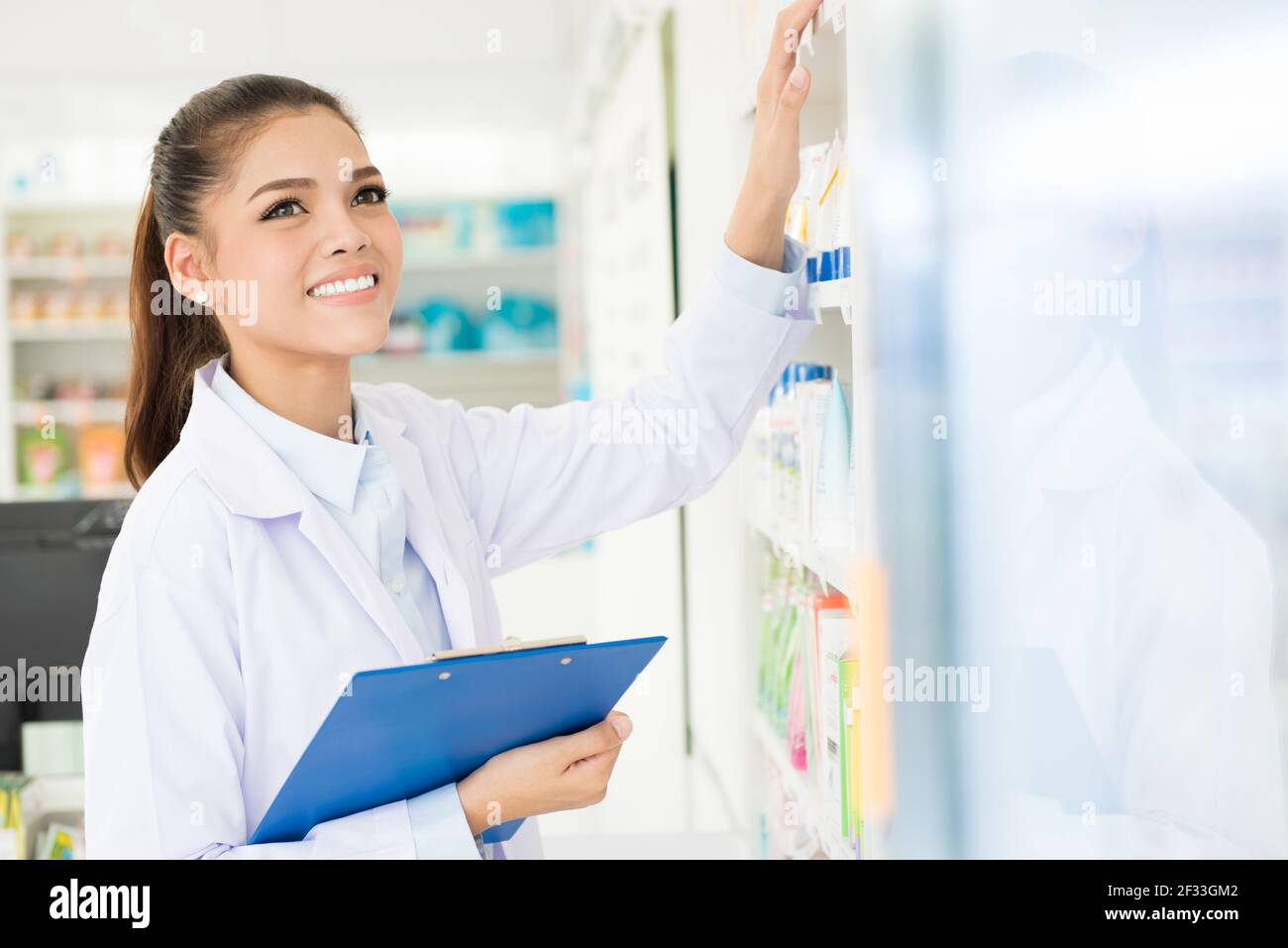 Lächelnde asiatische Frau Apothekerin in der Apotheke (Apotheke oder Drogerie) Stockfoto